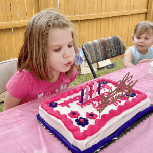 A young girl blowing out birthday cake candles